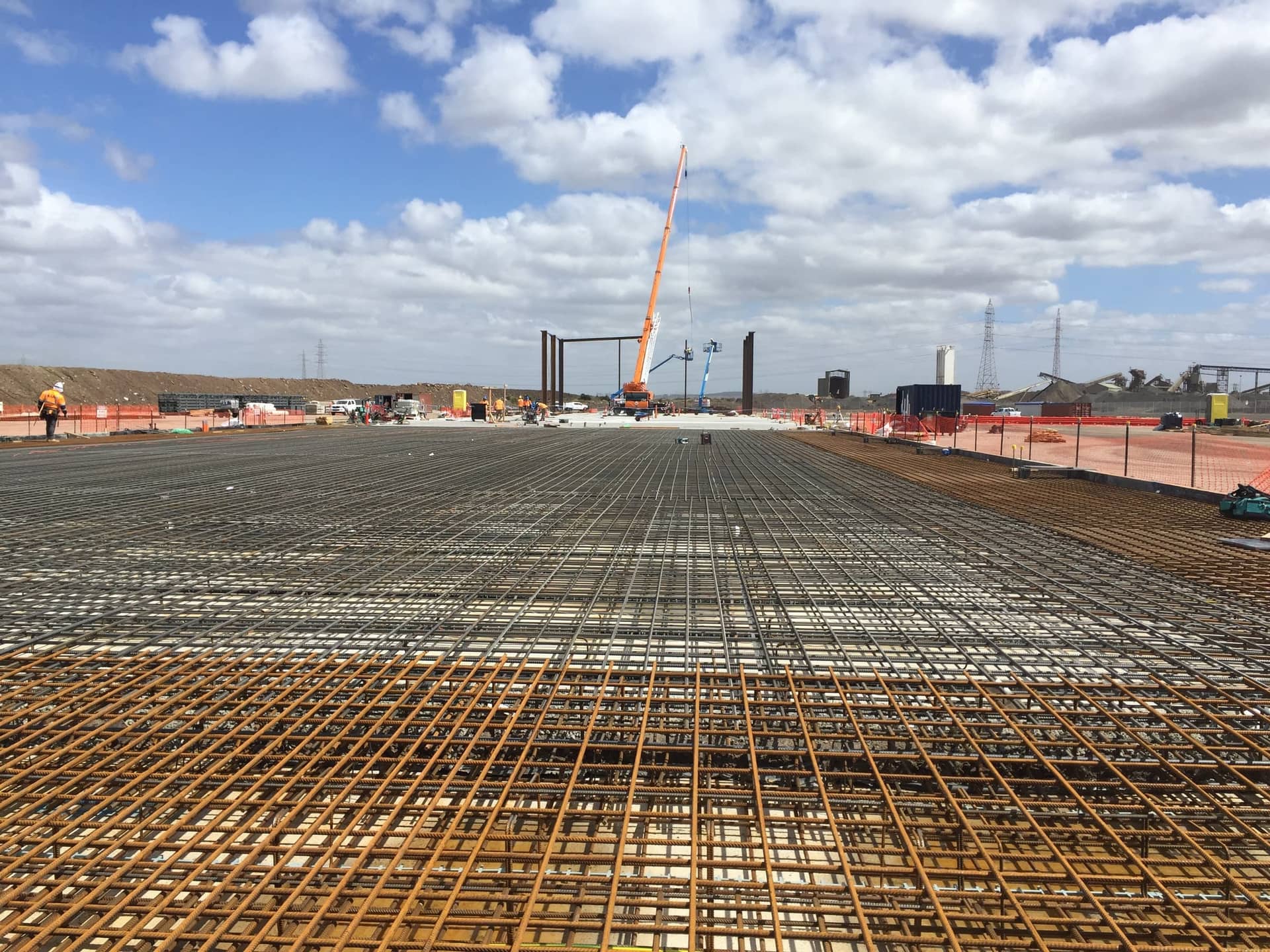 A large slab of fixed reinforcement stretching to a crane on the horizon