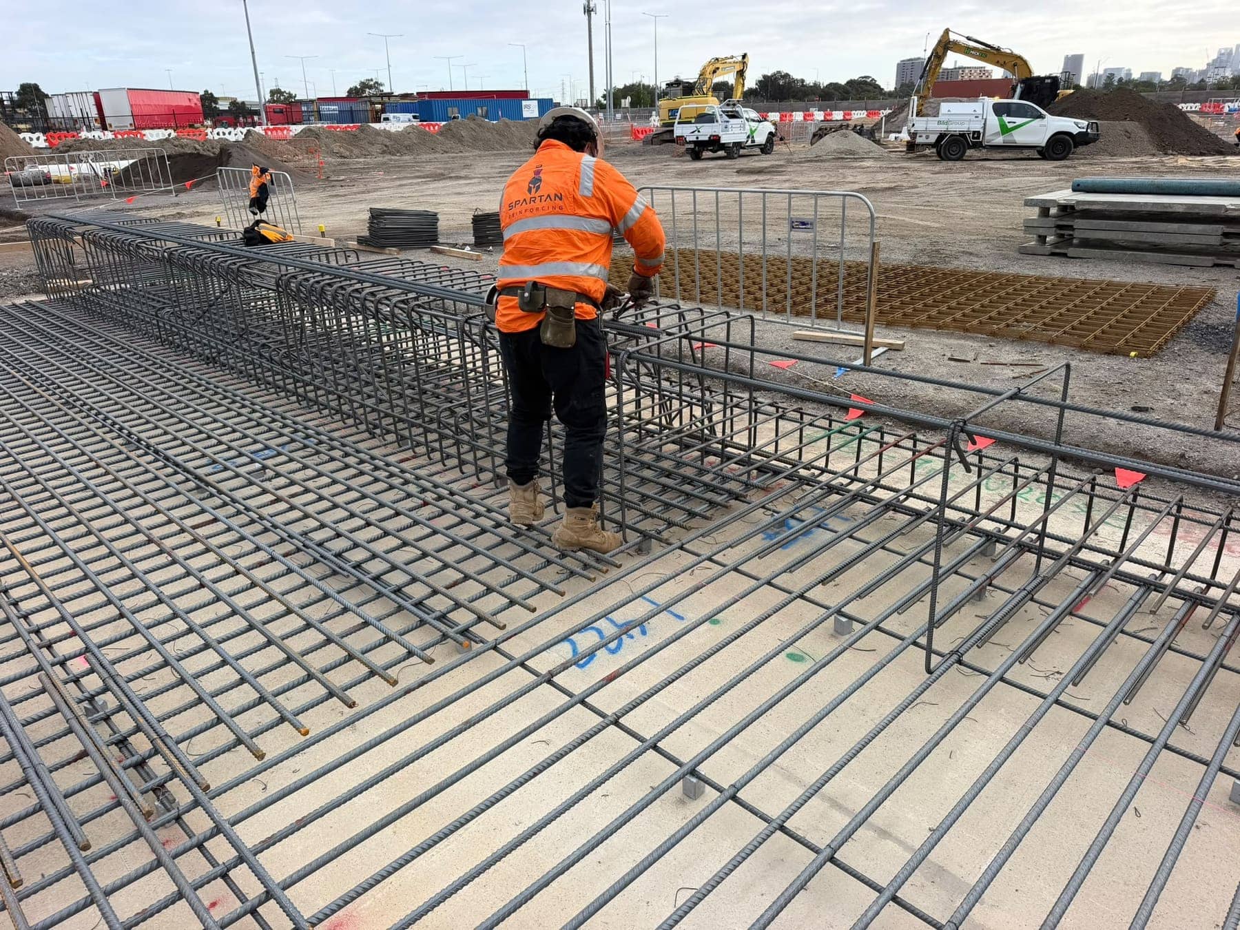 A Spartan steel fixer in a Spartan vest standing on reinforcement cages at Webb Dock